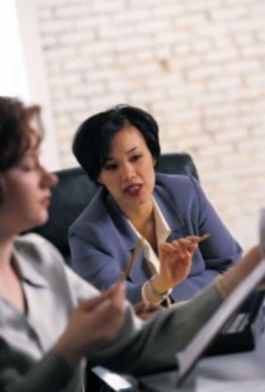 Two woman that work in the same company discuss to acquire interpretation services.