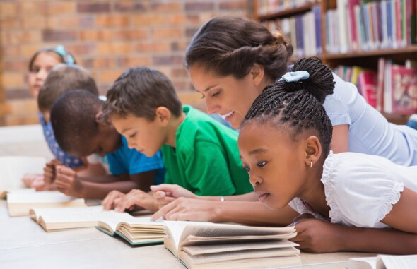 Maestra enseñando a estudiantes a leer en el Día Internacional de la Alfabetización.